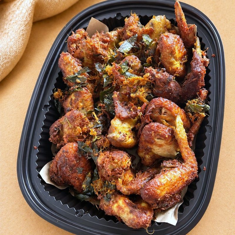 Ayam berempah &mdash; fried chicken wings coated in homemade rempah, in a black tray